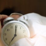 Main eteignant un reveil qui sonne au petit matin