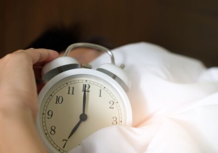Main eteignant un reveil qui sonne au petit matin