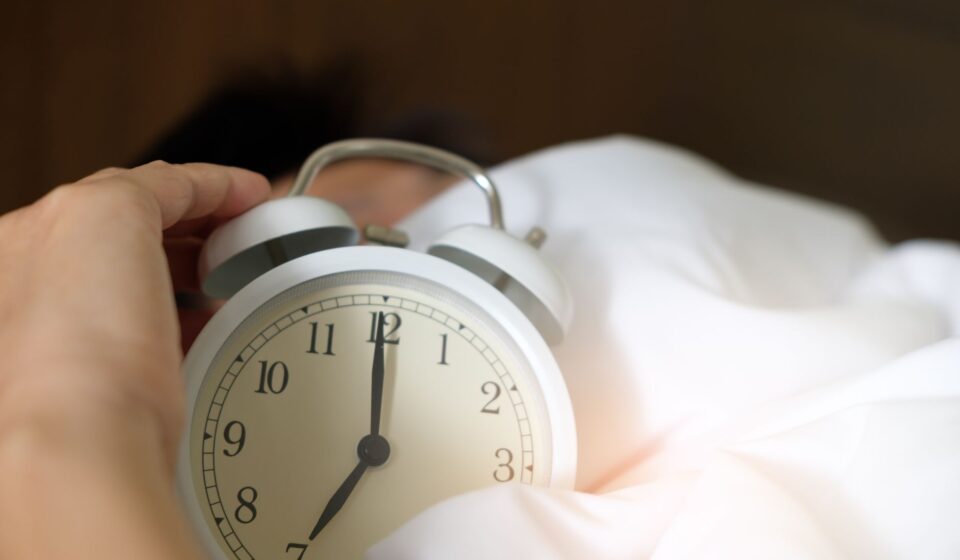 Main eteignant un reveil qui sonne au petit matin