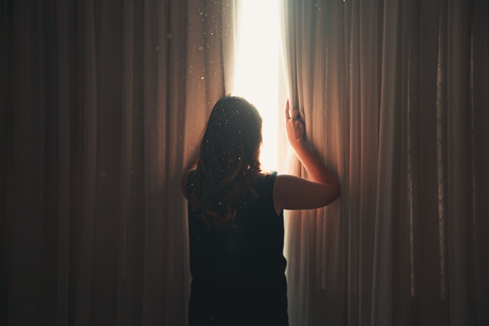Femme ouvrant les rideaux, lumière du matin dans la chambre