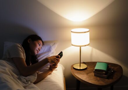 Bruit blanc, rose ou brun : lequel pour dormir ? Personne au lit consultant son smartphone le soir pres d une lampe