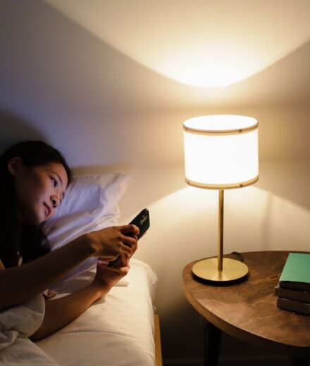 Bruit blanc, rose ou brun : lequel pour dormir ? Personne au lit consultant son smartphone le soir pres d une lampe