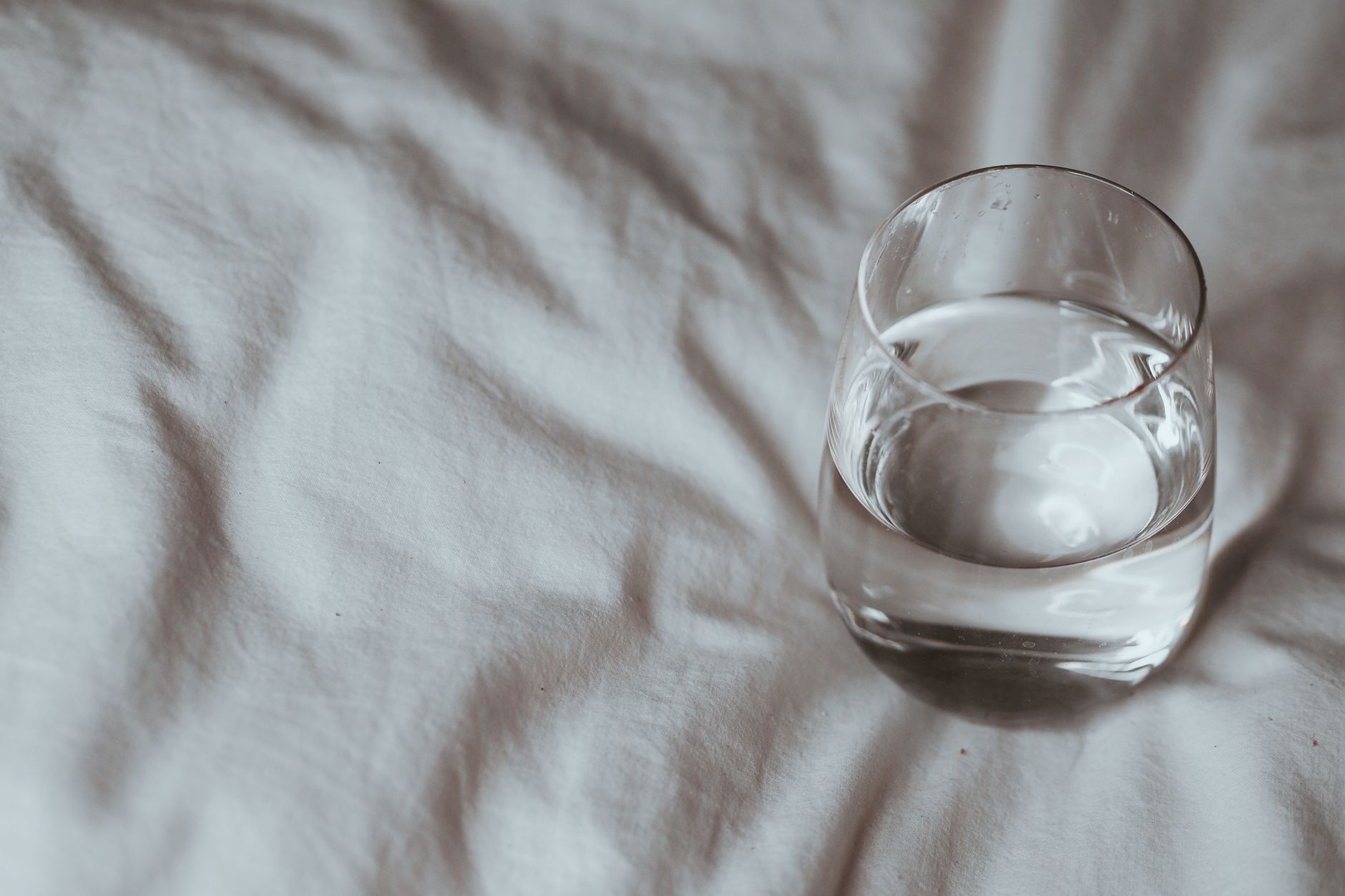 Verre d'eau posé sur une couette blanche
