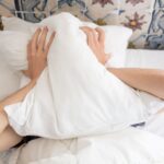 Alcool et sommeil : l’effet réel sur vos nuits Personne se couvrant le visage avec un oreiller au reveil