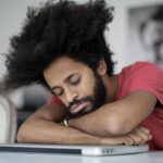 Sommeil polyphasique : mythe ou méthode efficace ? Homme endormi sur son ordinateur portable au bureau