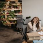 Cortisol : comment réguler l’hormone du stress Femme stressee assise a son bureau, tete dans les mains