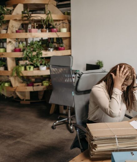 Femme stressee assise a son bureau, tete dans les mains