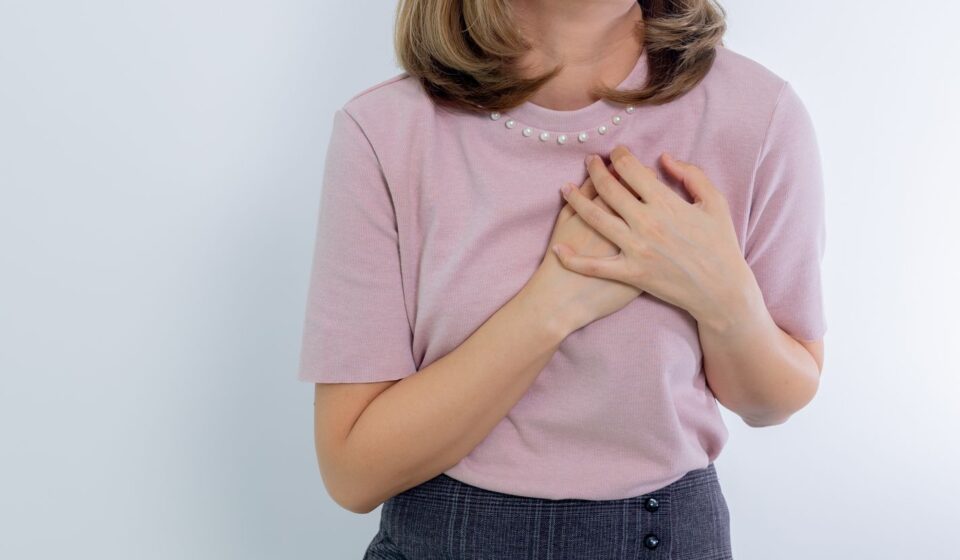 Femme portant la main a sa poitrine, respiration oppressee