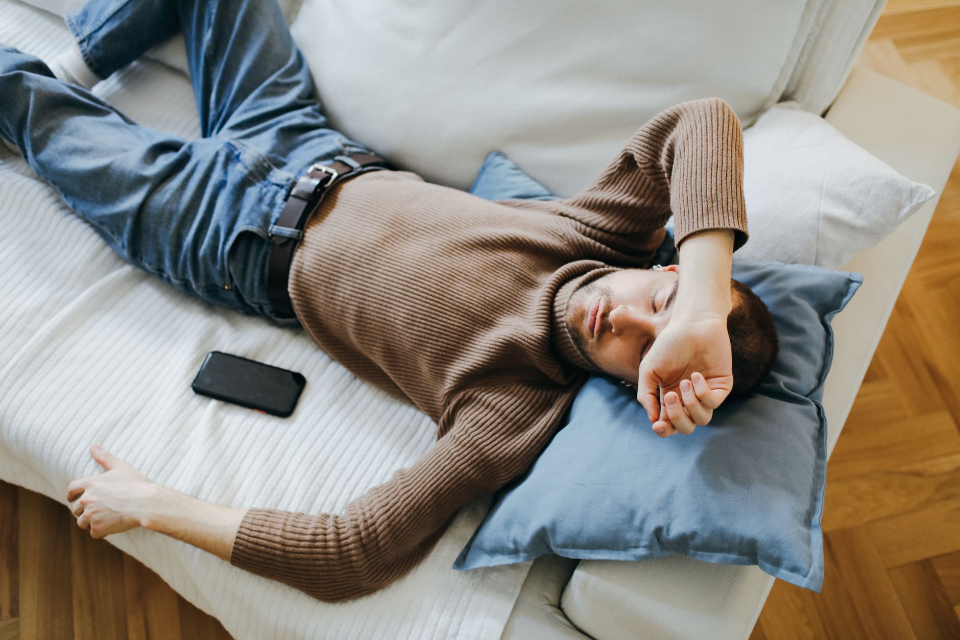 Homme faisant une courte sieste allongé sur un canapé en journée