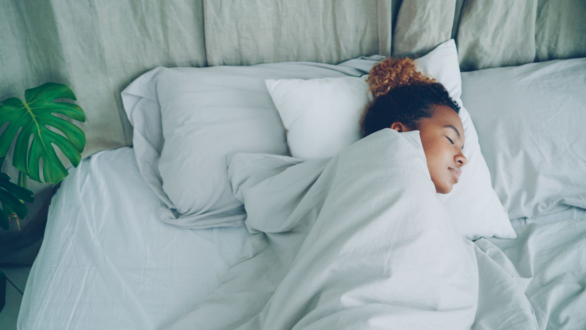 Femme endormie paisiblement dans une chambre aux draps blancs